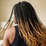Woman with long honey-tipped knotless box braids viewed from back, showing weight and swing in soft window light