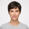 Woman with soft textured pixie cut showing piecey layers and tapered nape against white backdrop in beauty catalogue framing