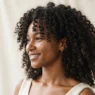 Woman with defined springy 3B curls against a soft ivory backdrop in three quarter view with diffused light